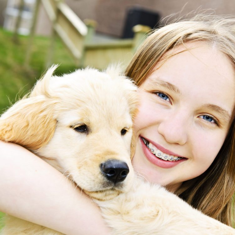 Girl with braces hugging her dog