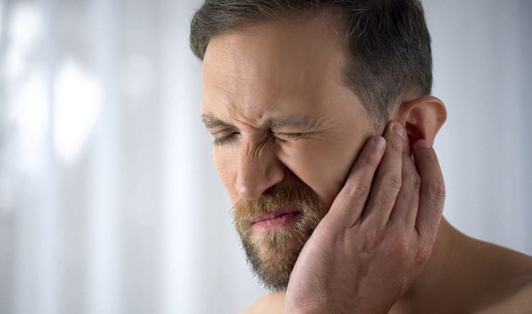 Man holding his aching ear due to ear pain