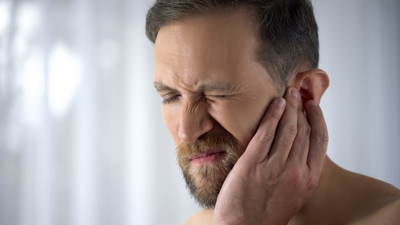 Man holding his aching ear due to ear pain